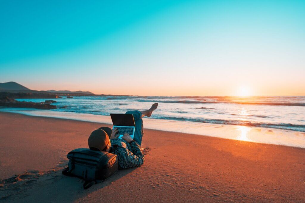 Man sitting on a beach with his laptop